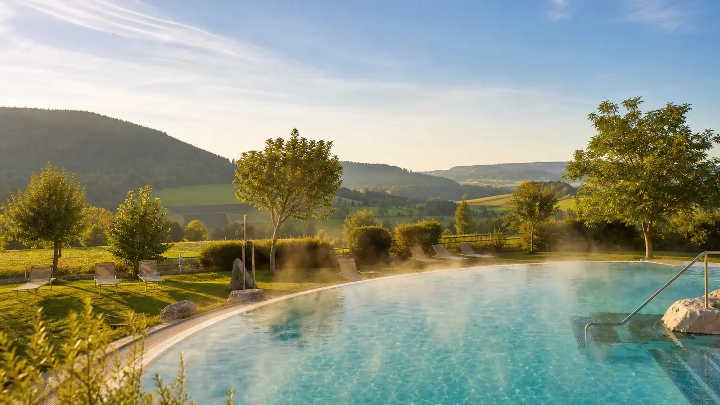 Thermalbad Außenbecken in Süddeutschland mit Blick auf grüne Hügellandschaft im Sommer