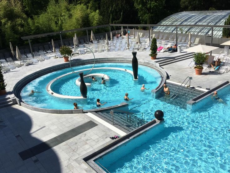 Thermalbad Außenbecken am Abend mit dampfendem Wasser und beleuchtetem Thermengebäude in Süddeutschland