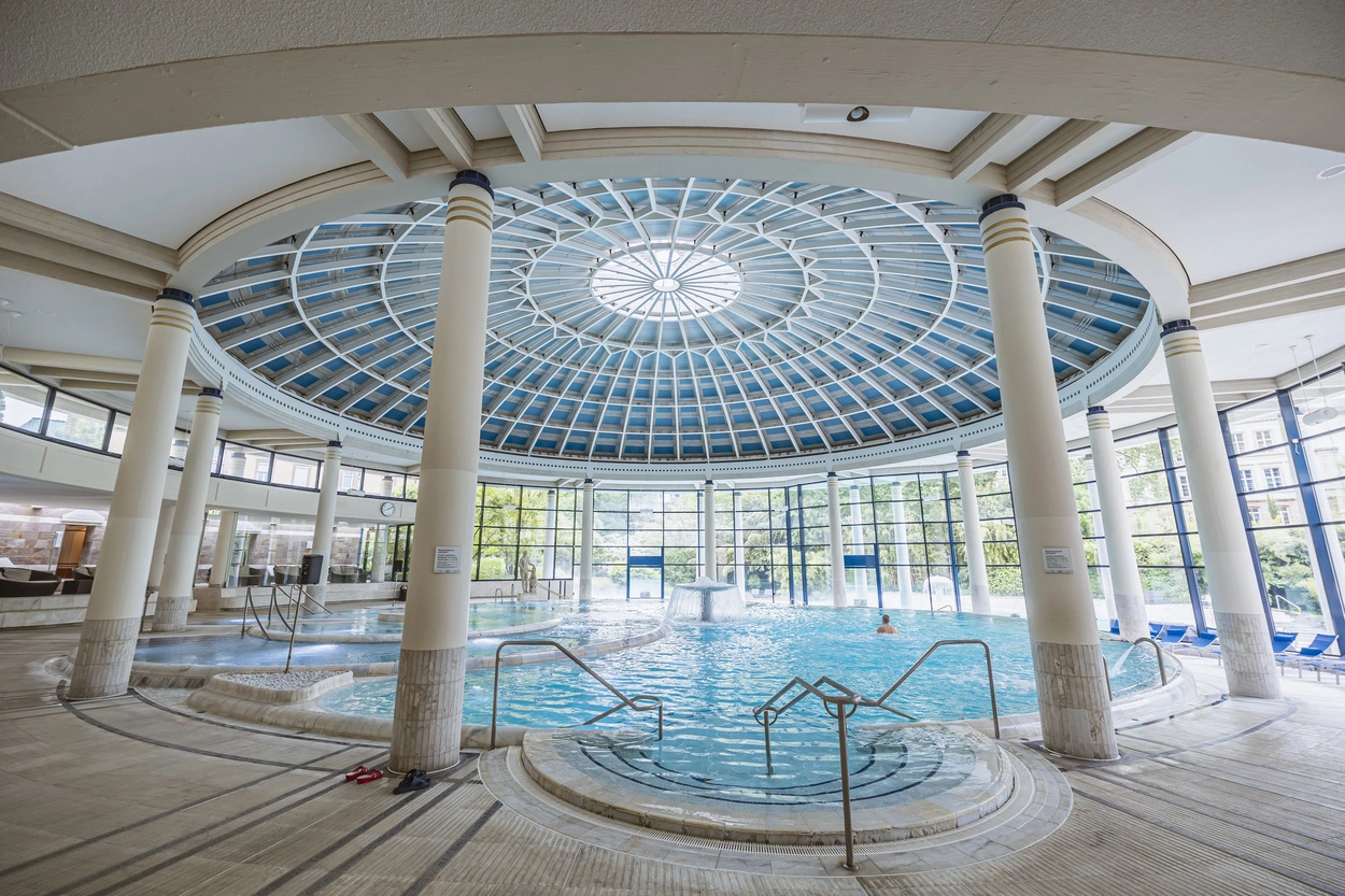 Innenbereich der Caracalla Therme Baden-Baden mit großem Thermalbecken unter einer beeindruckenden Glaskuppel und weißen Säulen